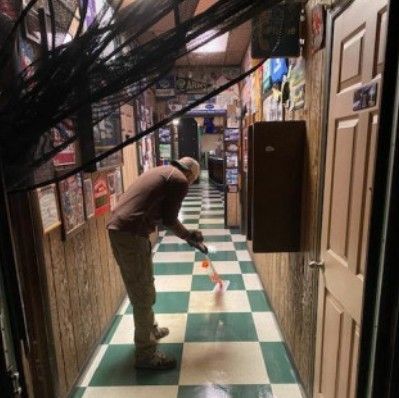 A man is cleaning a checkered floor in a hallway.