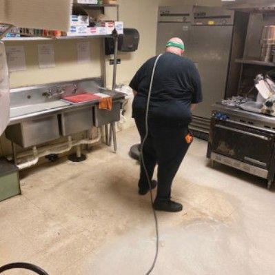 A man is cleaning a kitchen floor with a vacuum cleaner