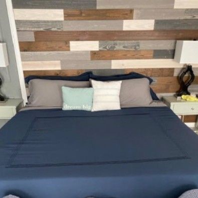 A bed with a blue comforter and pillows in a bedroom with a wooden headboard.
