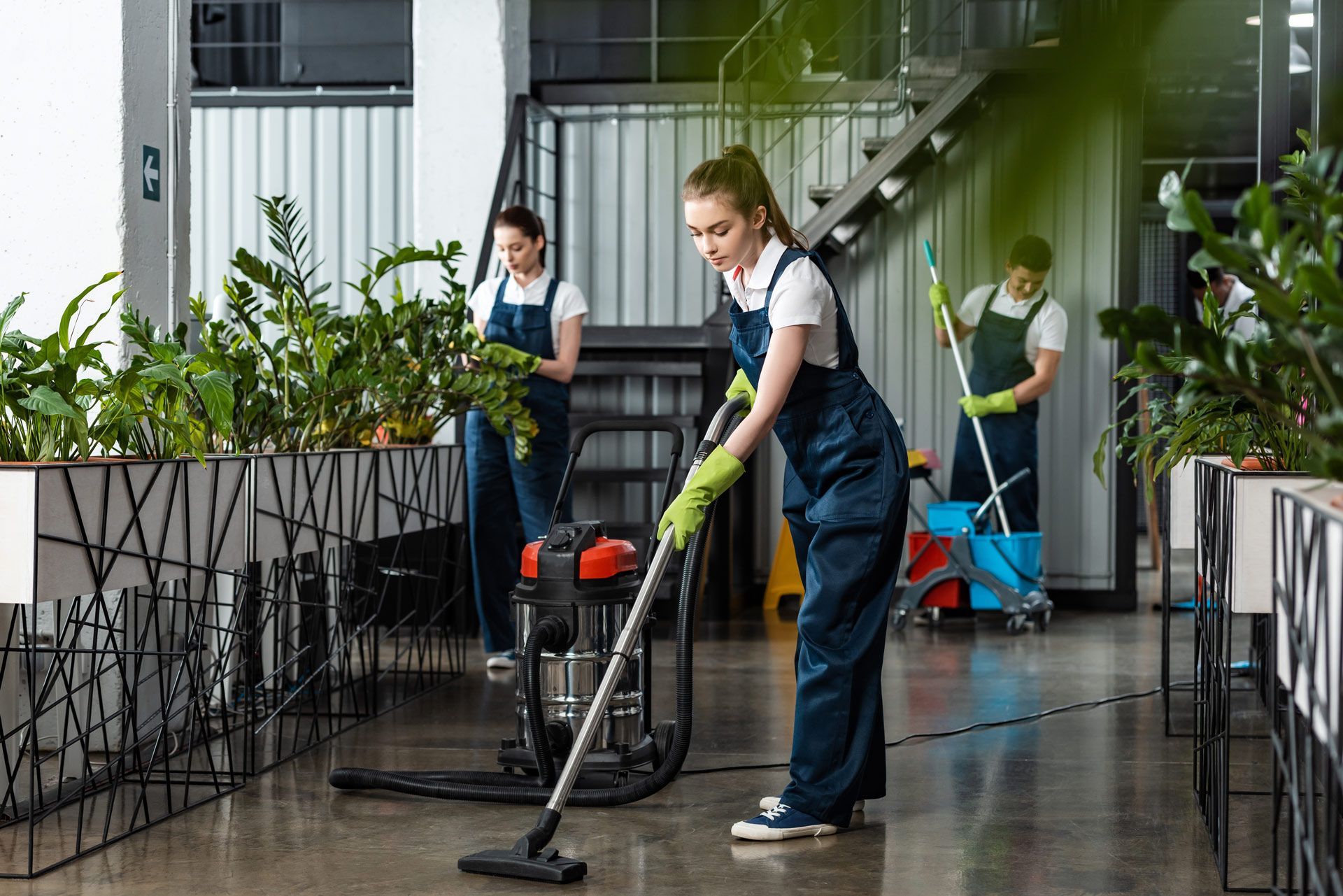 A woman is cleaning the floor with a vacuum cleaner in an office.