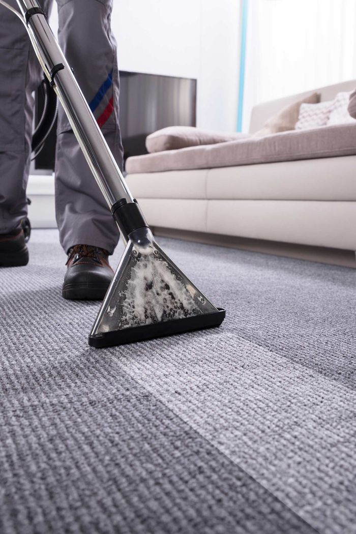 A person is using a vacuum cleaner to clean a carpet in a living room.