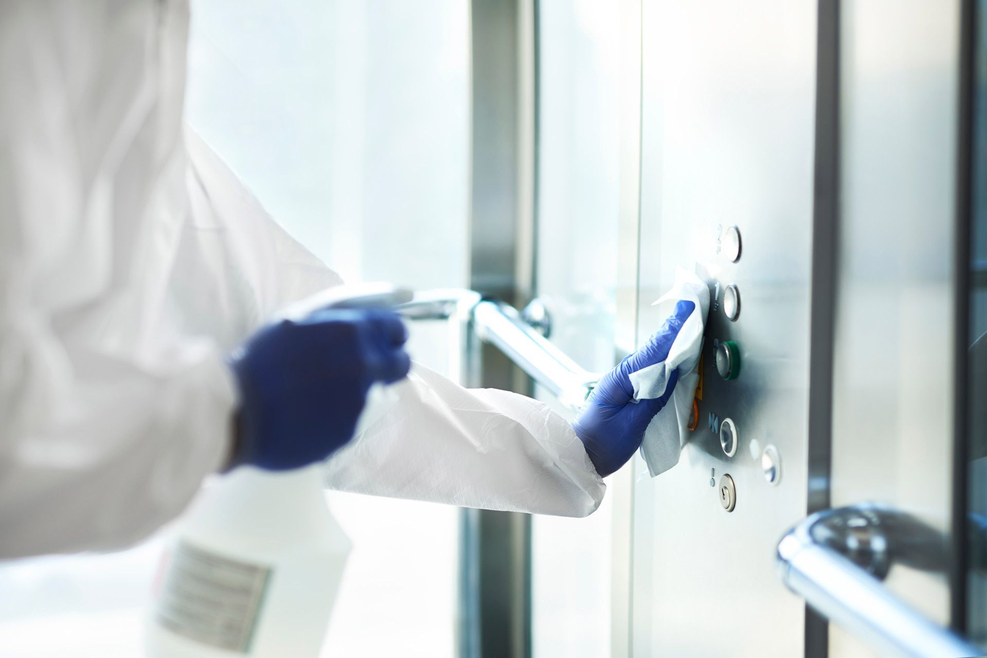 A person is cleaning an elevator with a spray bottle.