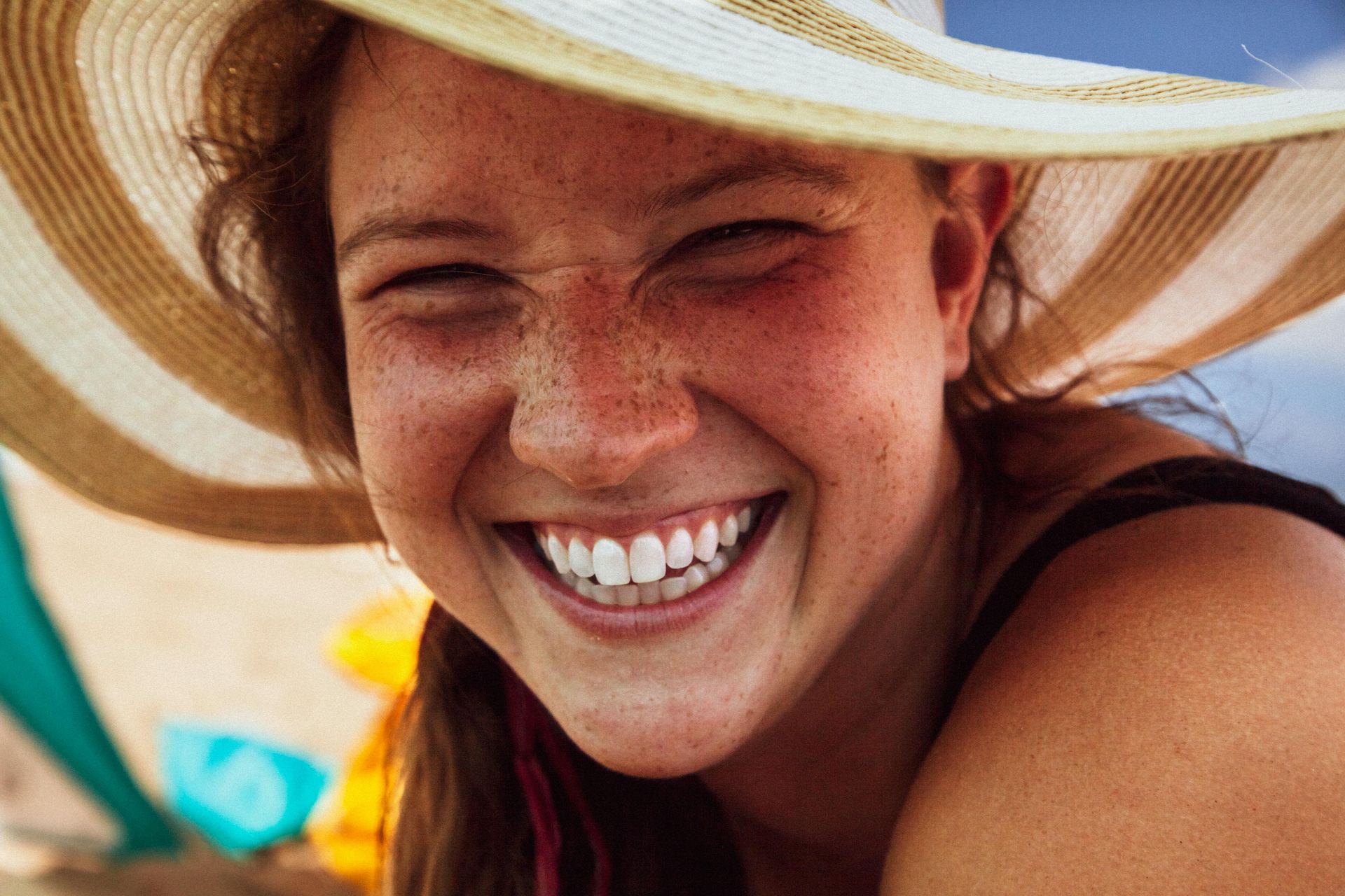 A close up of a woman wearing a hat and smiling.