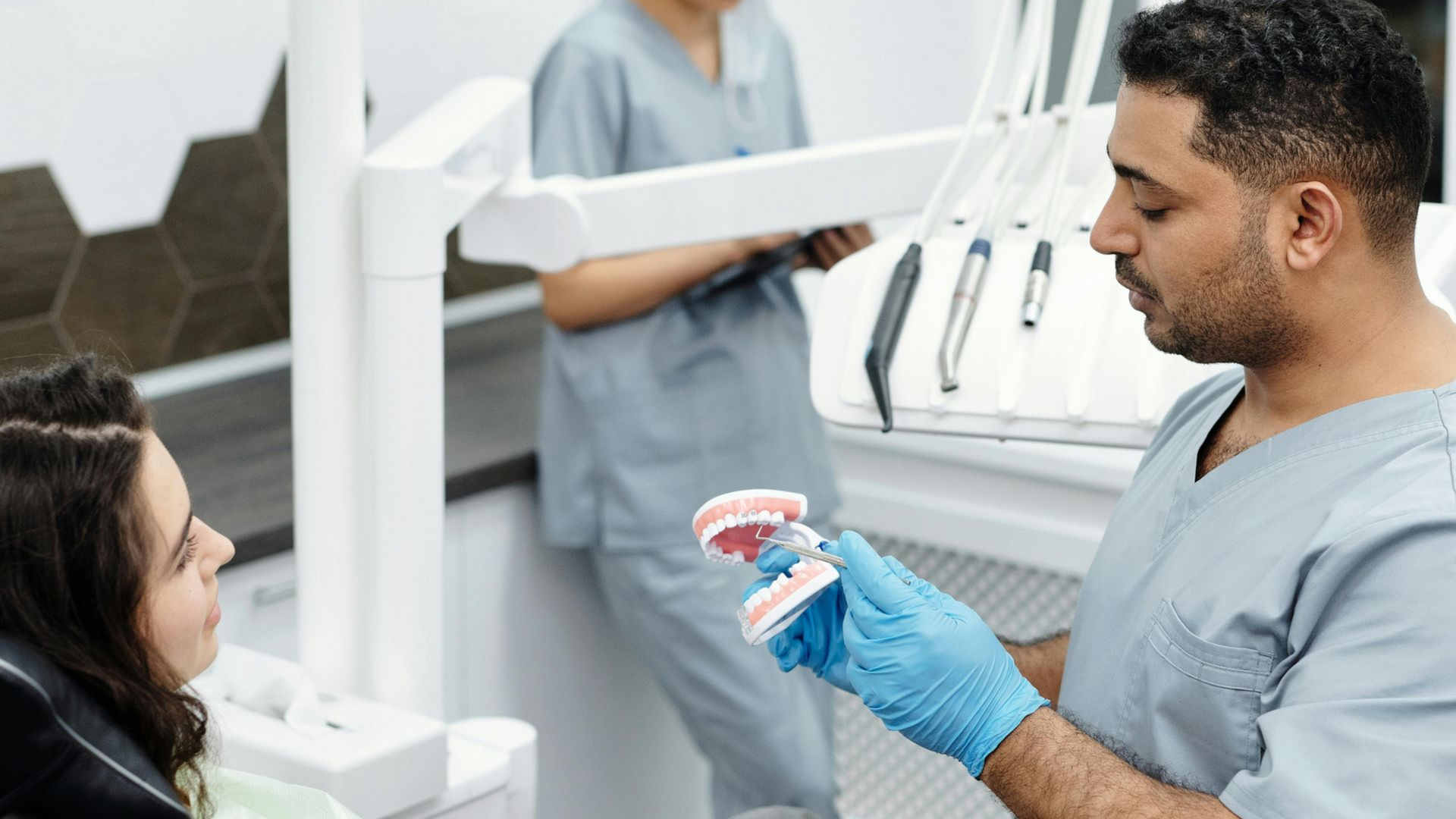 Dentist holding a model of teeth and showing patient details of teeth