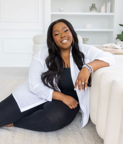 Anisha Angella, CEO and Founder, The Early Childhood Coach leaning on a couch in a studio