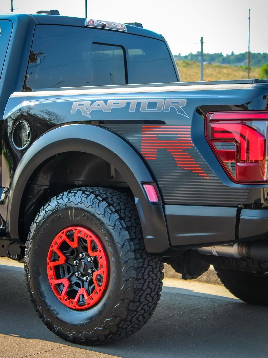 Black Ford Raptor pickup truck with red accents on wheels and side graphics.