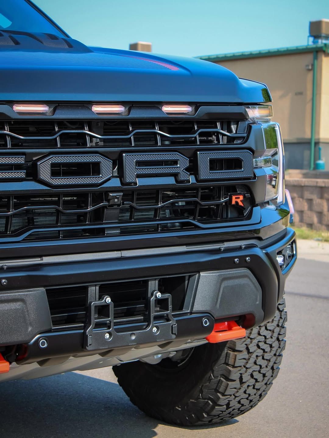Black Ford Raptor truck's front grill and tire. The