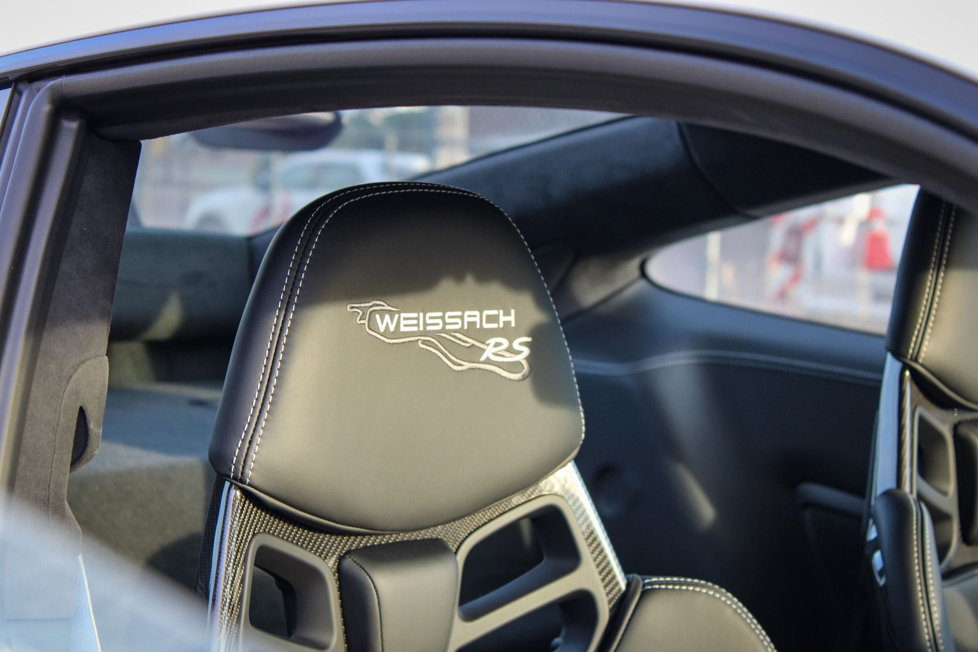 Red and white Ford Bronco parked on a residential street with trees.