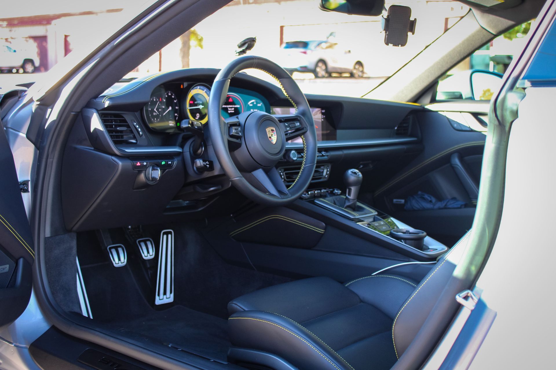A person cleaning a black truck's front grill with a gray cloth. The truck has the letter