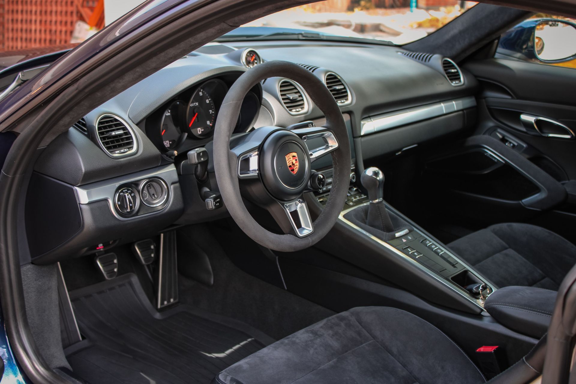 Interior of a black Porsche sports car, including steering wheel, dashboard, seats, and gear shift.