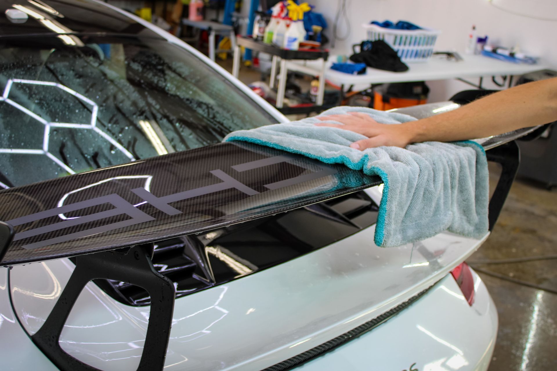 Person washing a black truck with a spray nozzle at a car wash.
