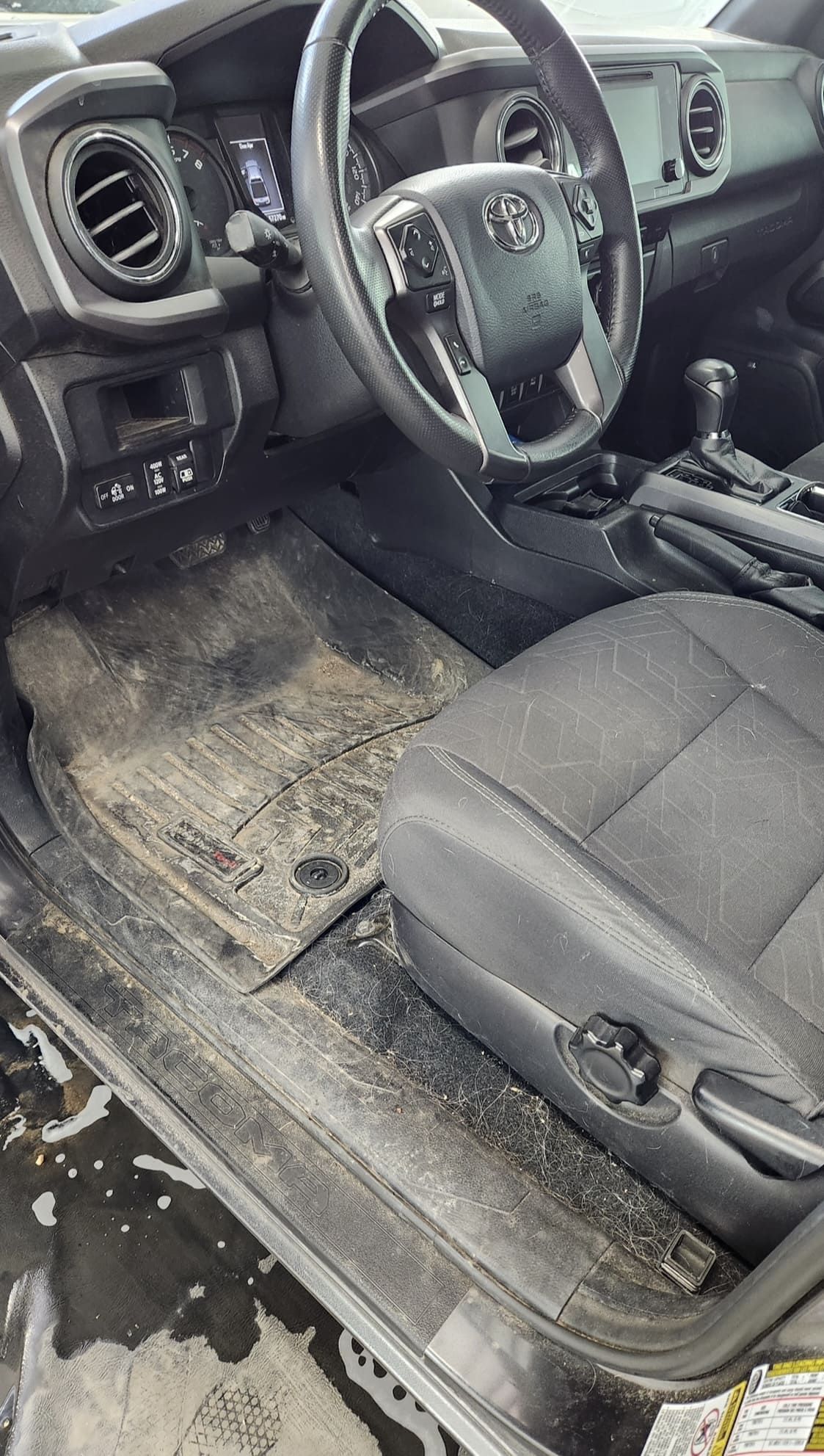 Dirty car interior; muddy floor mat, steering wheel, and front seat are visible.