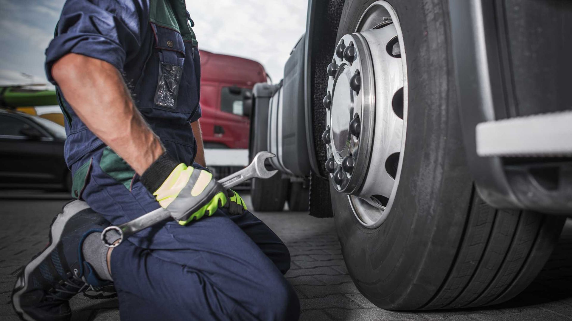 a mechanic holding a wrench next to a car's wheel