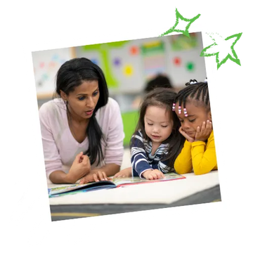 A teacher reads a book with two young students at a table. The children are diverse and focused on the book.