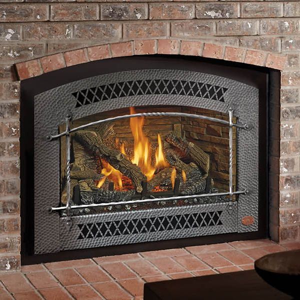 A fireplace with a metal frame and a brick wall