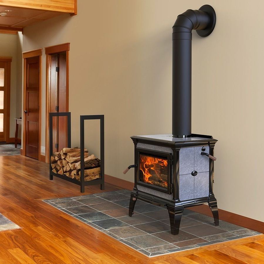 A wood stove in a living room next to a log rack