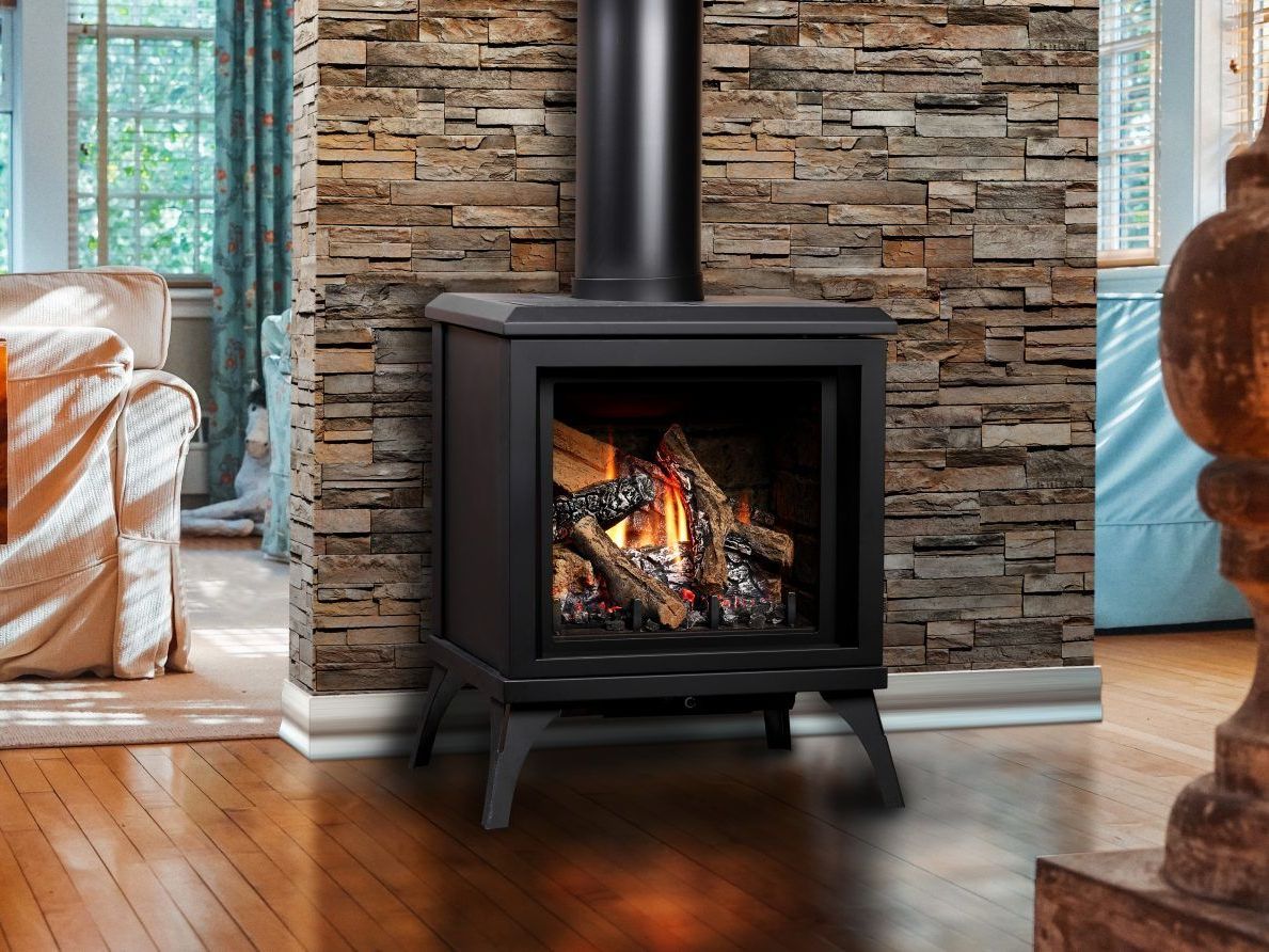 A gas fireplace is sitting in a living room next to a stone wall.