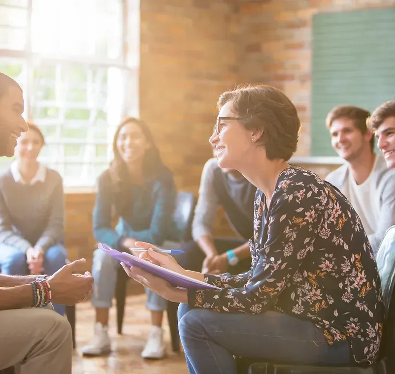Group Of People Are Sitting In A Circle Talking To Each Other — NDIS Support Coordinator In Svensson Heights, QLD