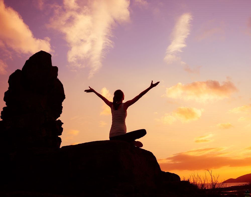 Woman Is Sitting On A Rock With Her Arms Outstretched At Sunset — NDIS Support Coordinator In Svensson Heights, QLD