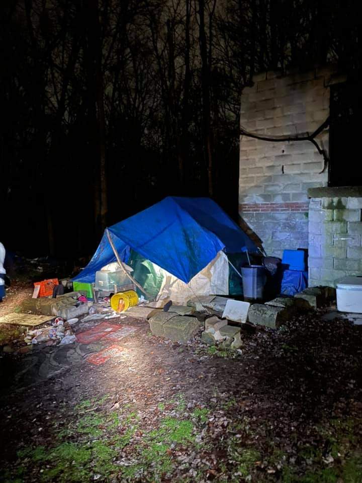 A blue tarp is covering a tent in the woods at night.