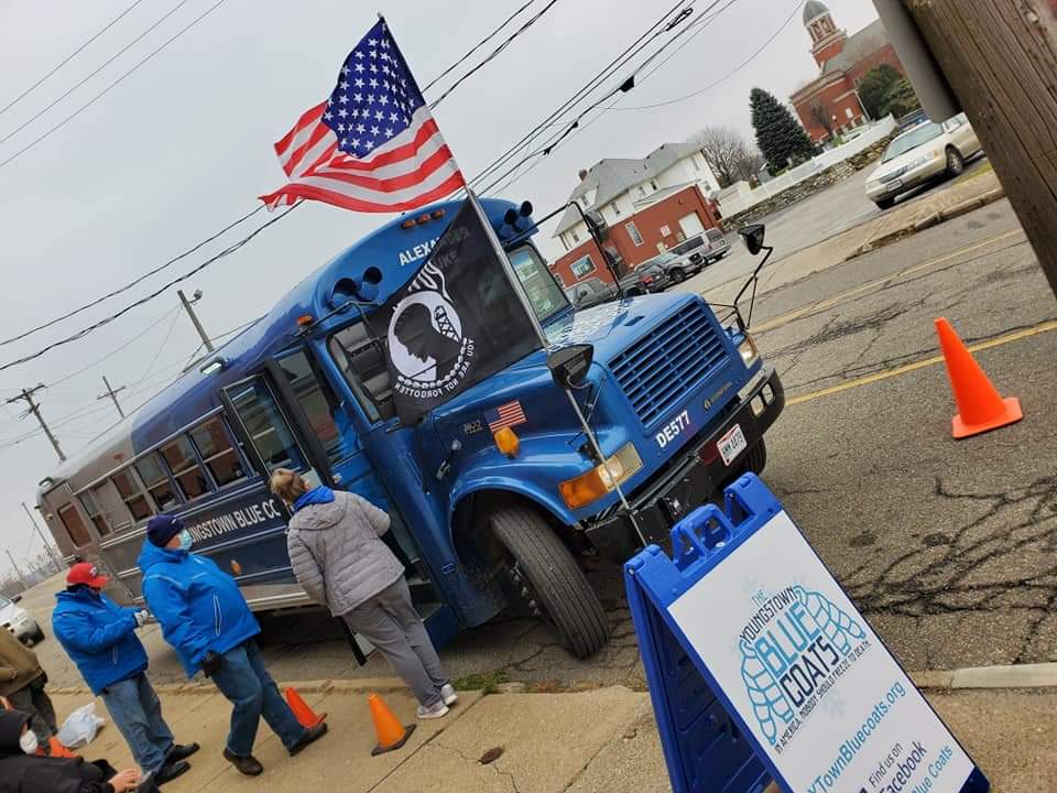 A blue bus is parked on the side of the road