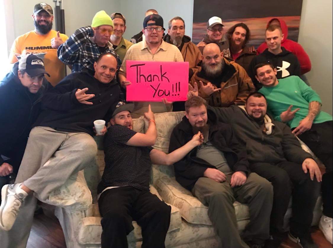 A group of men sitting on a couch holding a thank you sign