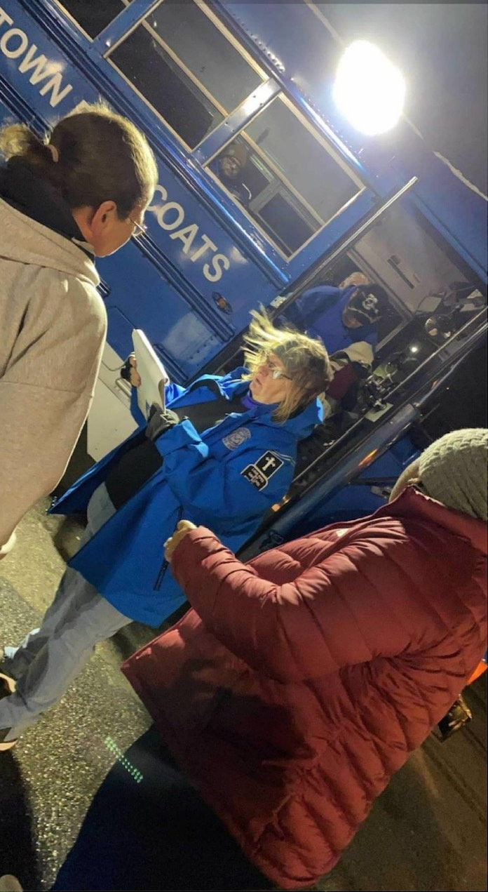 A group of people are standing in front of a blue bus.