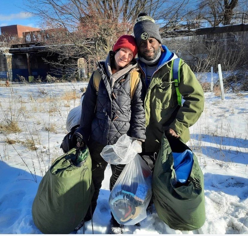 A man and a woman standing in the snow holding bags