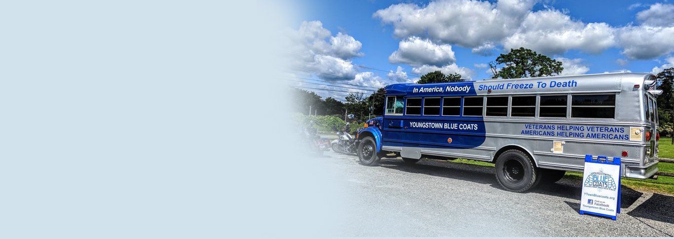 A blue and silver school bus is parked on a gravel road.