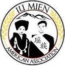 Logo for the Iu Mien American Association, featuring traditional figures, mountains, and text in a circular border.