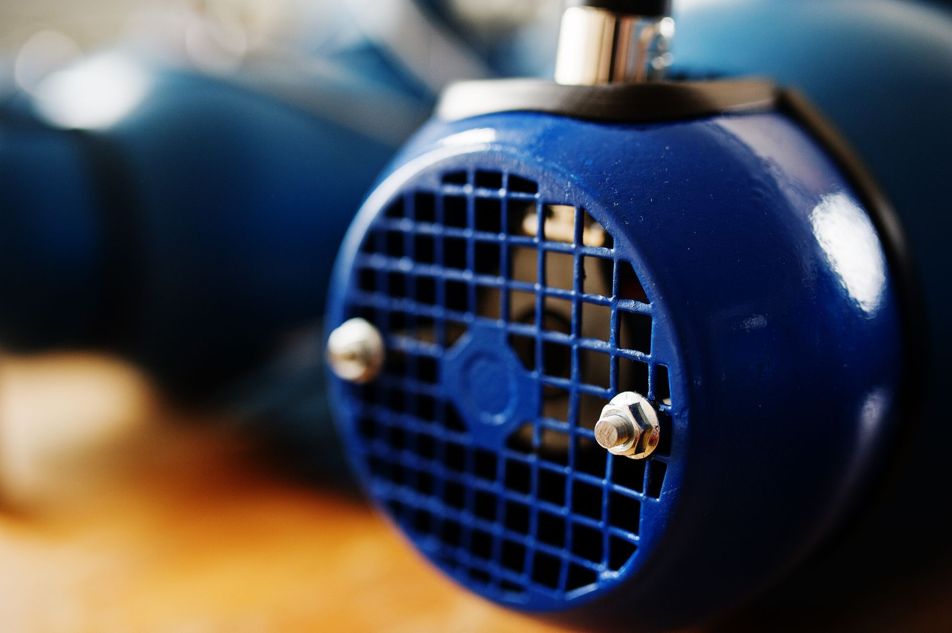 Blue electric motor with a gridded cooling vent and two silver screws.