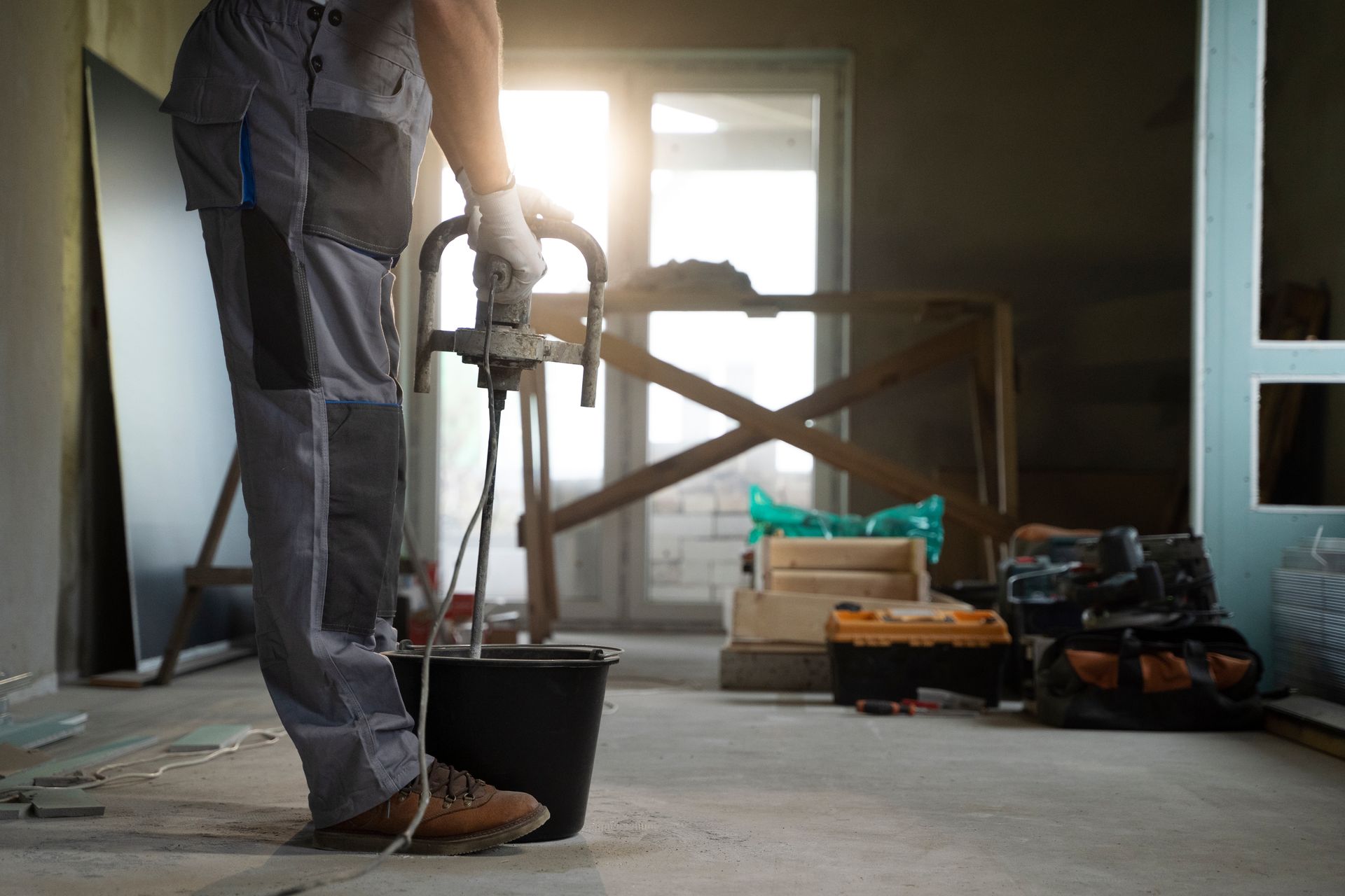 Person mixing material with a power mixer in a construction site.