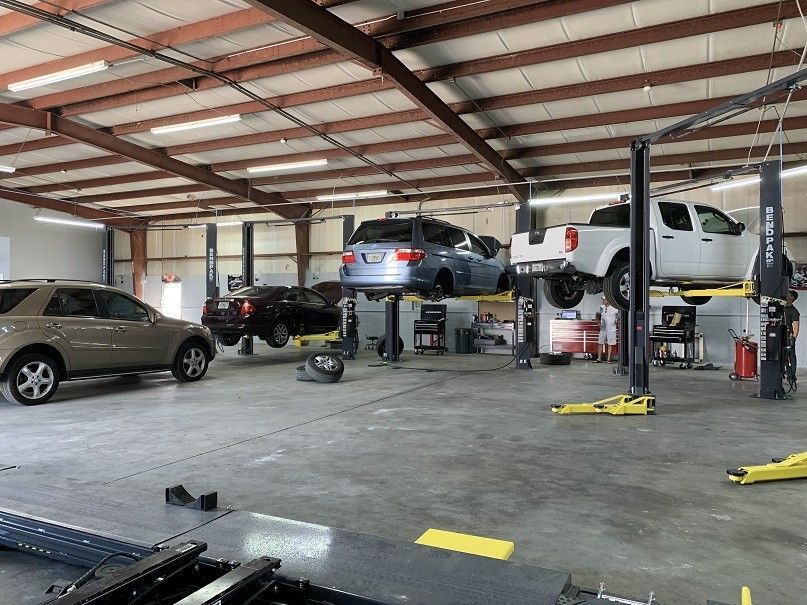 A lot of cars are being worked on in a garage.