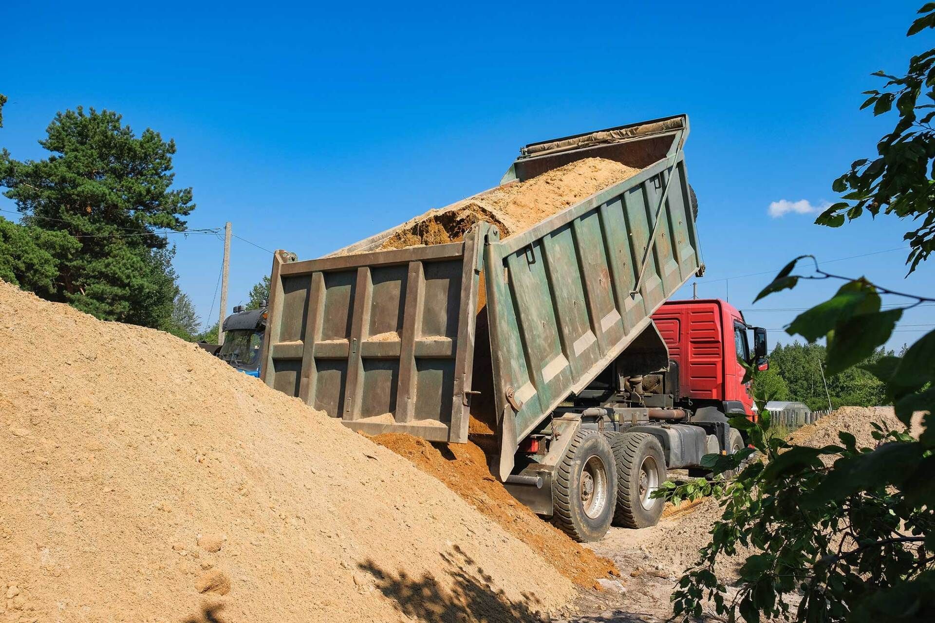 dump truck unloading sand gravel at construction site
