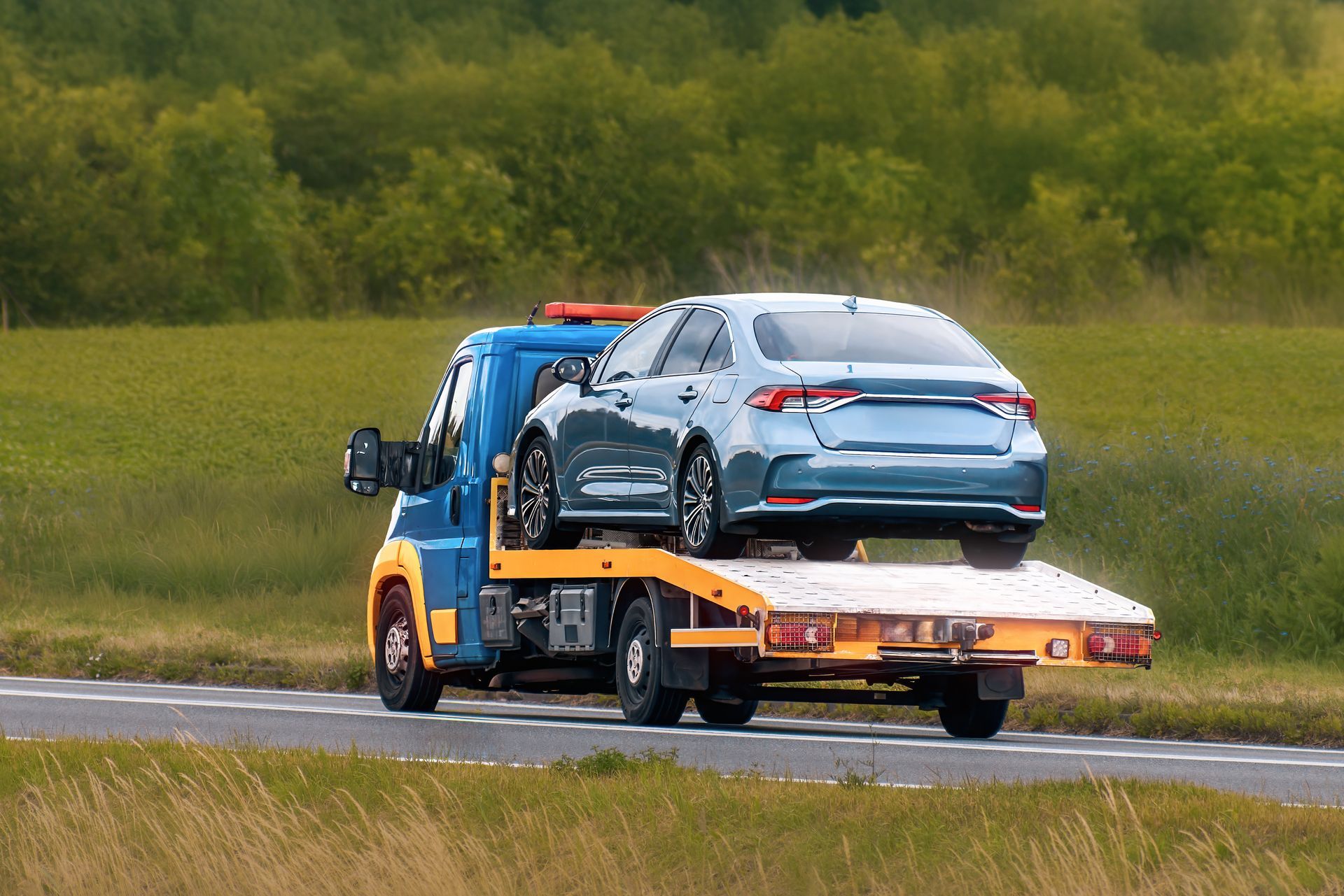 A blue car on top of a tow truck, showcasing professional towing services.