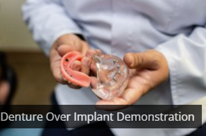 Dentist holding a dental mold, explaining to a patient in a medical office.
