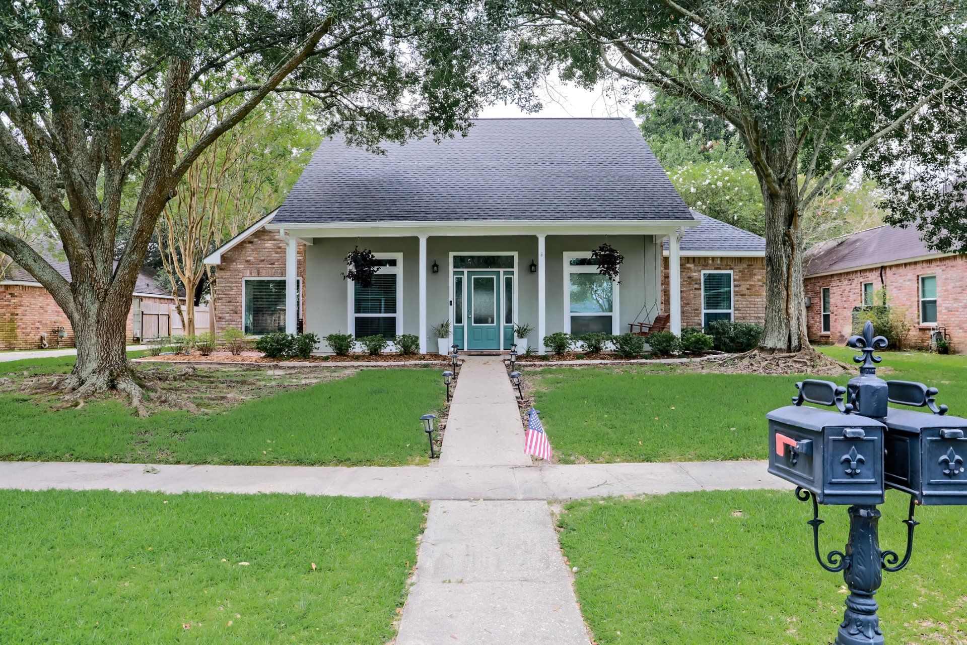 A brick house with a blue door and a mailbox in front of it.