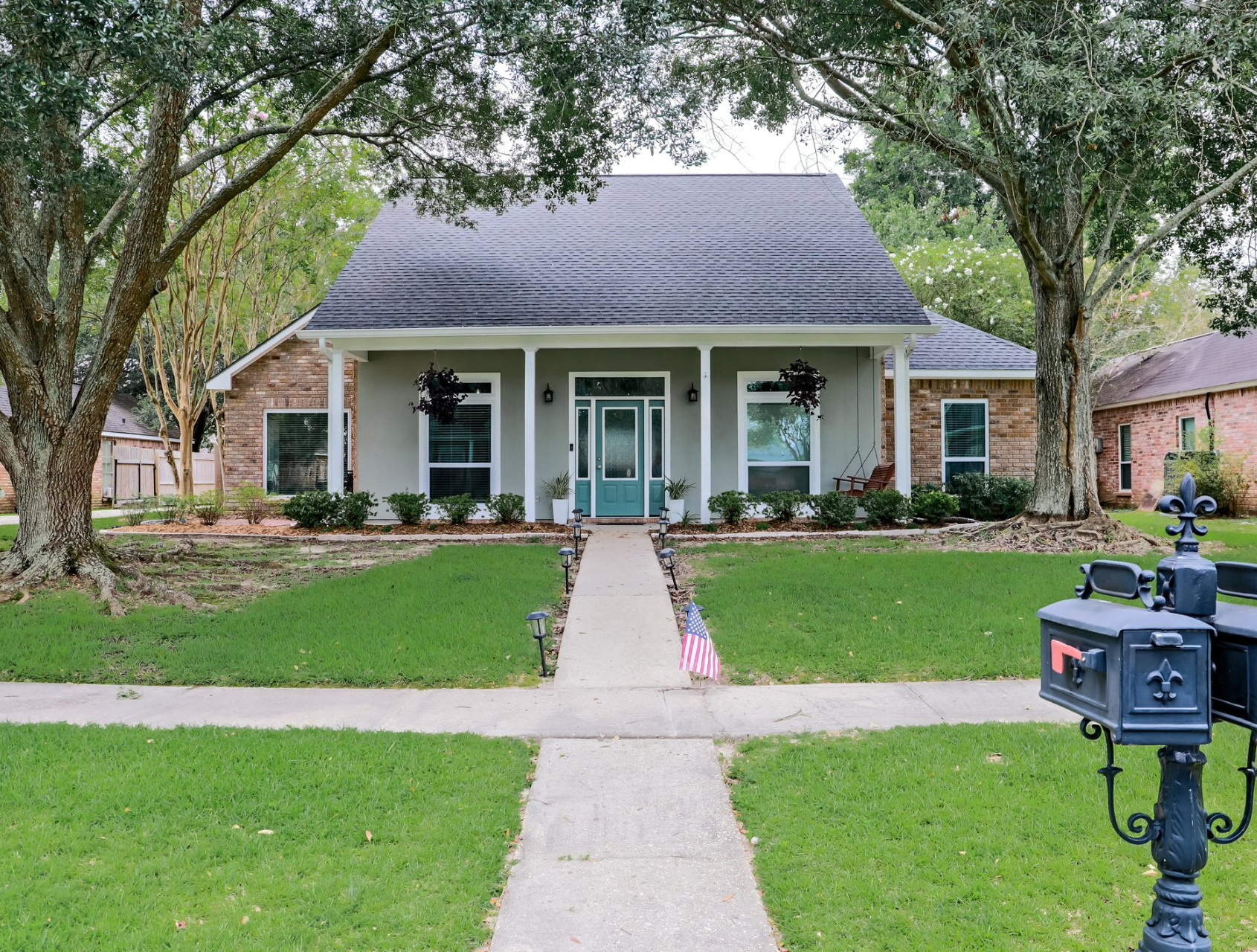 A brick house with a blue door and a mailbox in front of it.