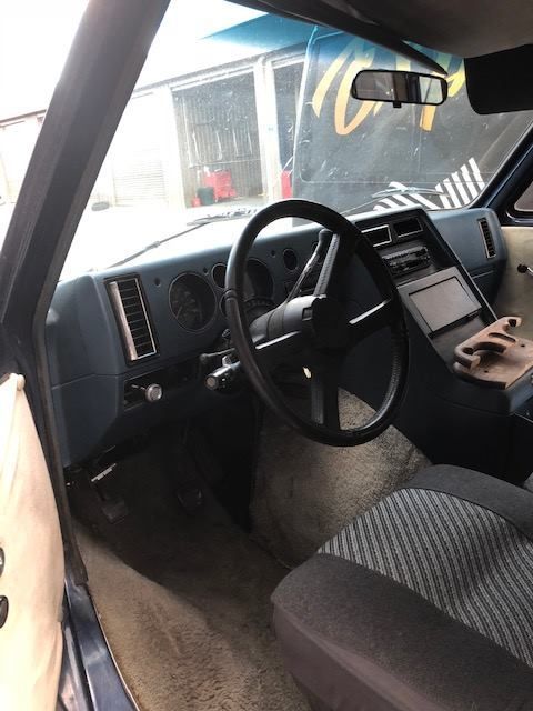 Interior of a blue van, showing steering wheel, dashboard, seats, and a view through the windshield.