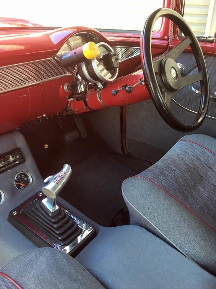 Red classic car interior with custom gauges, steering wheel, and gear shift.