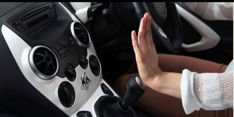 Person's hand raised in front of car's dashboard, possibly stopping something.