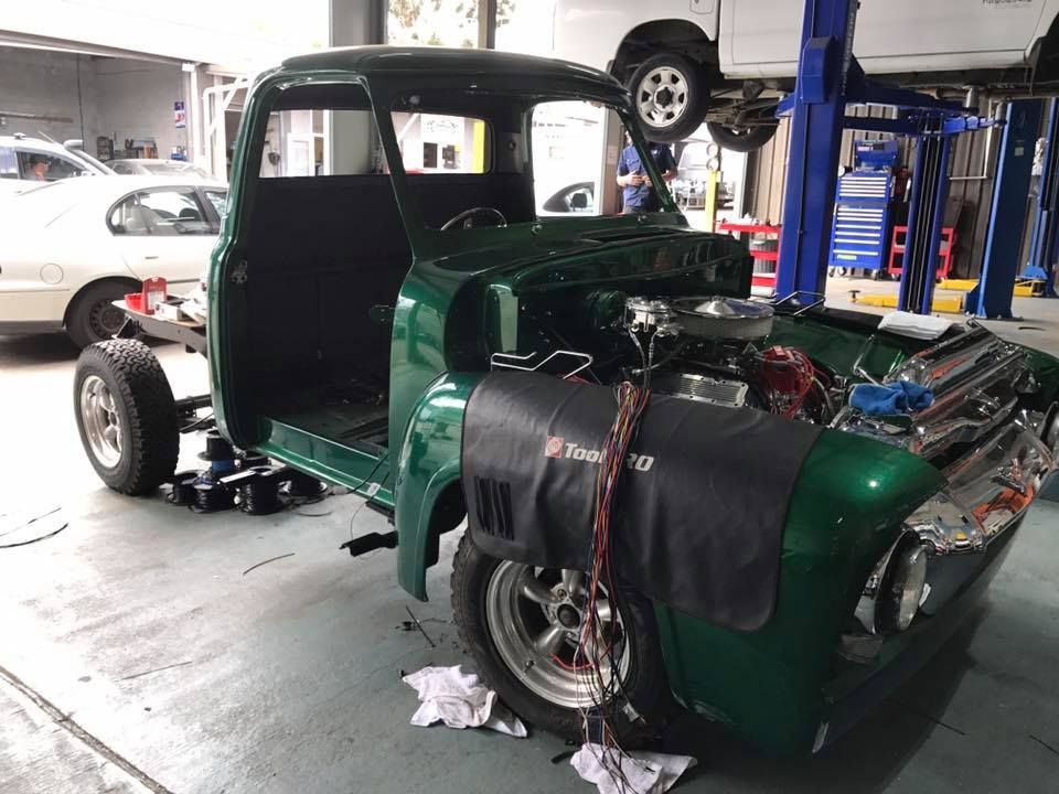 Green vintage truck in a repair shop.