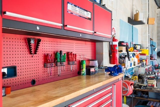 Red and black workshop with tools, pegboard, storage, and a workbench.