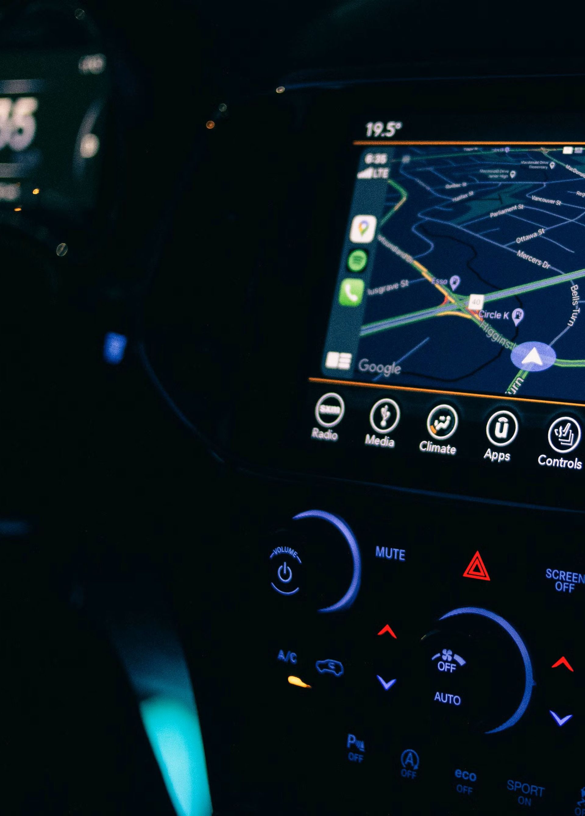 Mechanic working on car engine in a garage; wearing headlamp, holding a rag.