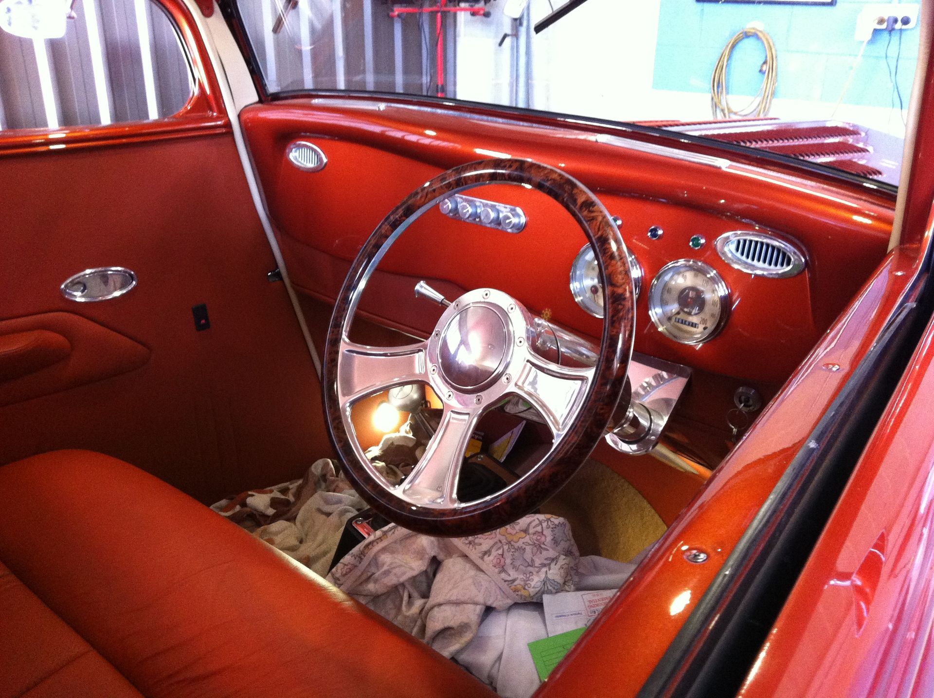 Red classic car interior with wood-grain steering wheel, chrome accents, and leather seating.