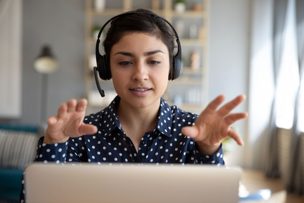 Woman Wearing Headset Gestures With Hands, Looking at a Laptop — Tech Aid In Moffat Beach, QLD