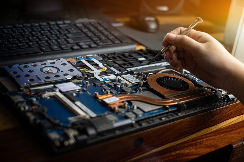 Person Using a Screwdriver to Repair a Laptop's Motherboard; Close-up View — Tech Aid In Moffat Beach, QLD