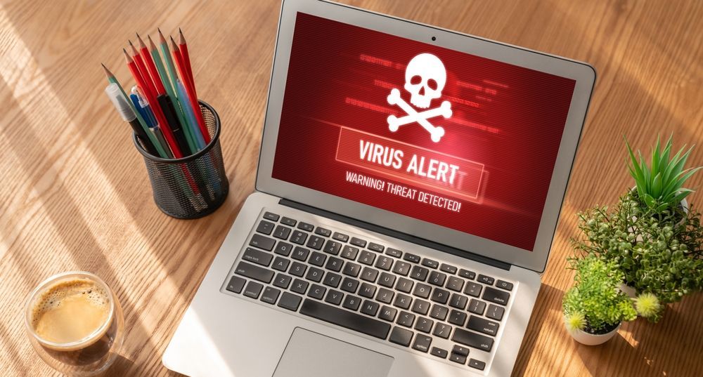 Laptop Displaying Virus Alert on a Desk Next to Coffee and a Plant — Tech Aid In Moffat Beach, QLD