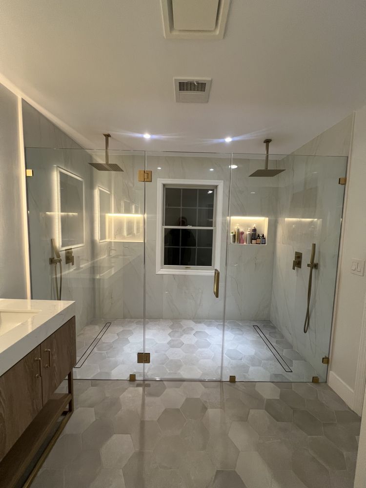 Modern bathroom with a large walk-in glass shower, hexagonal floor tiles, and two rainfall showerheads.