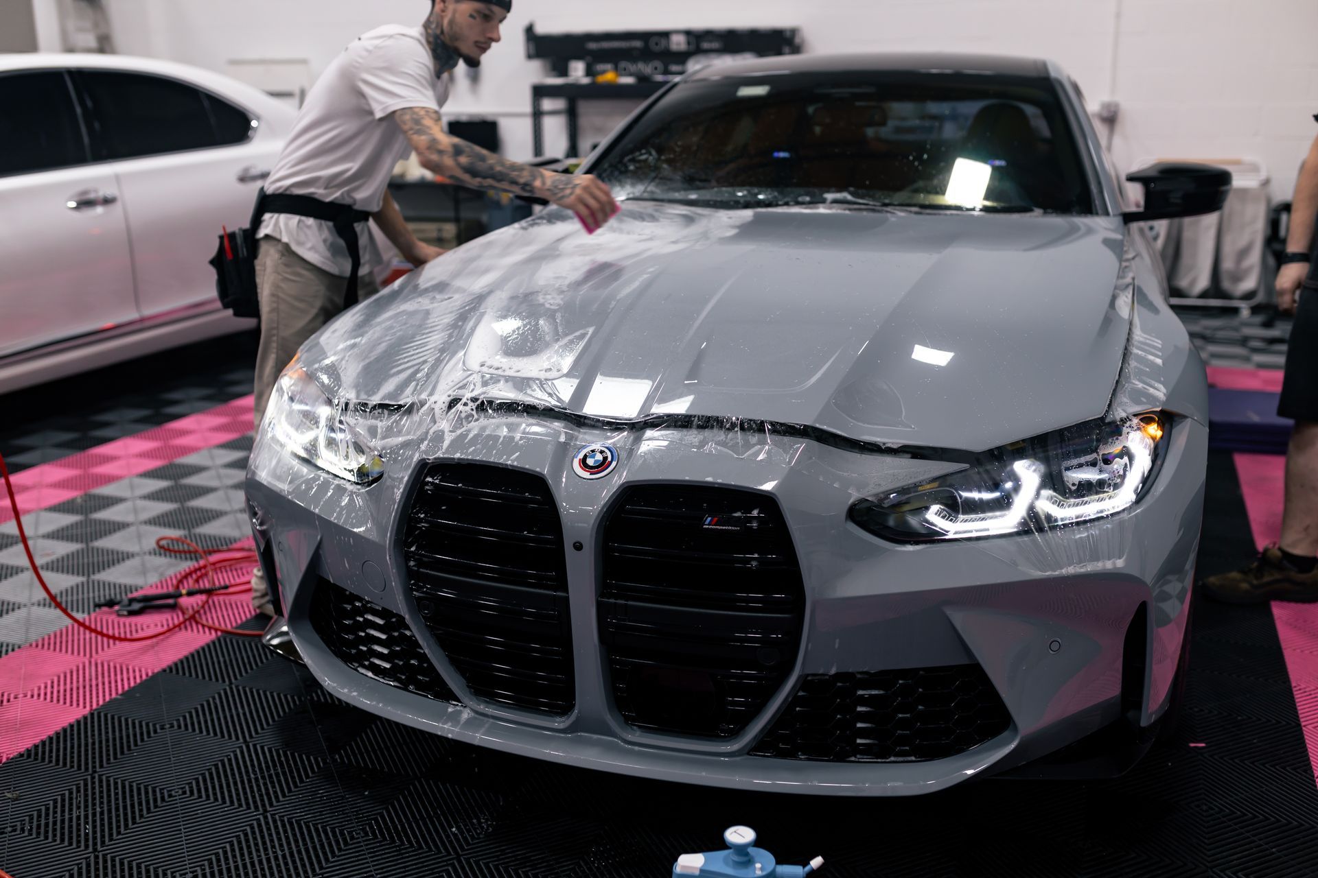 A man is applying a protective film to the front of a bmw m4.